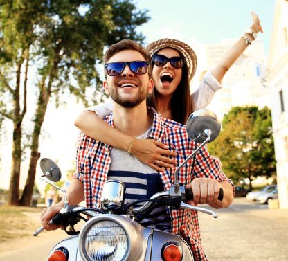 a man and a woman riding on the back of a scooter.