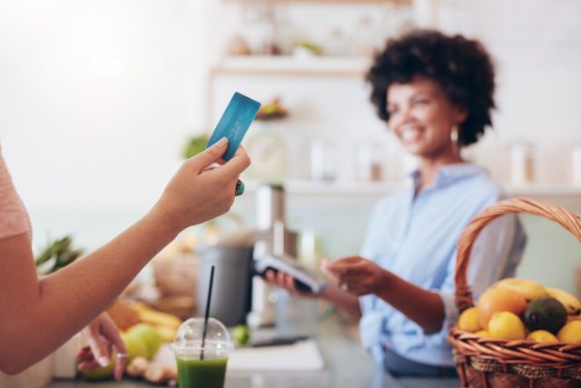 a woman holding a credit card in a kitchen.